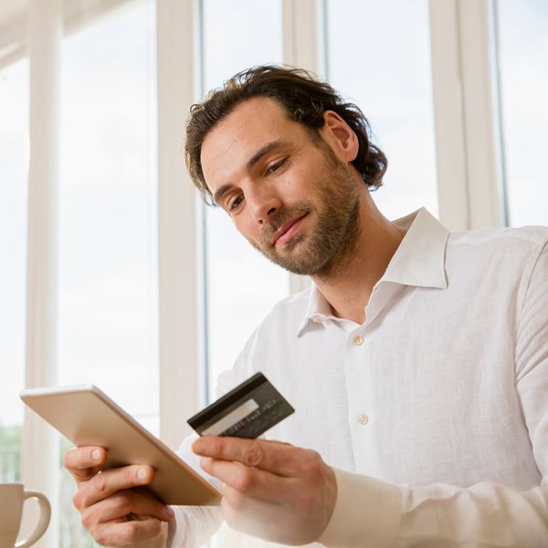 Hombre mirando tarjeta de débito y teléfono