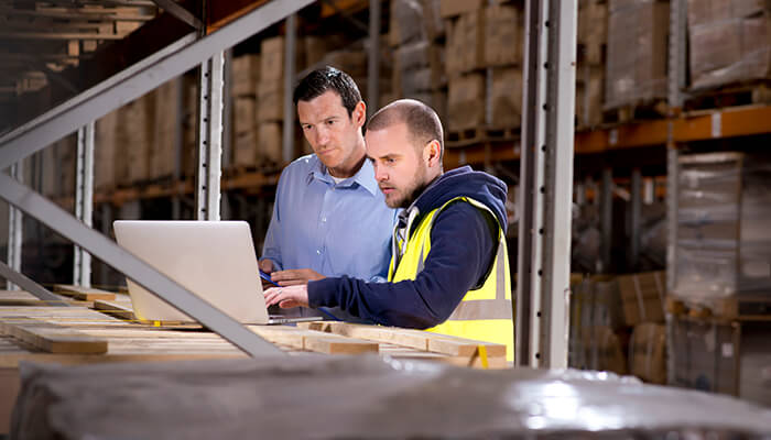Men in warehouse looking at computer