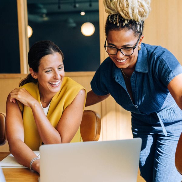 Two women smiling and looking at laptop