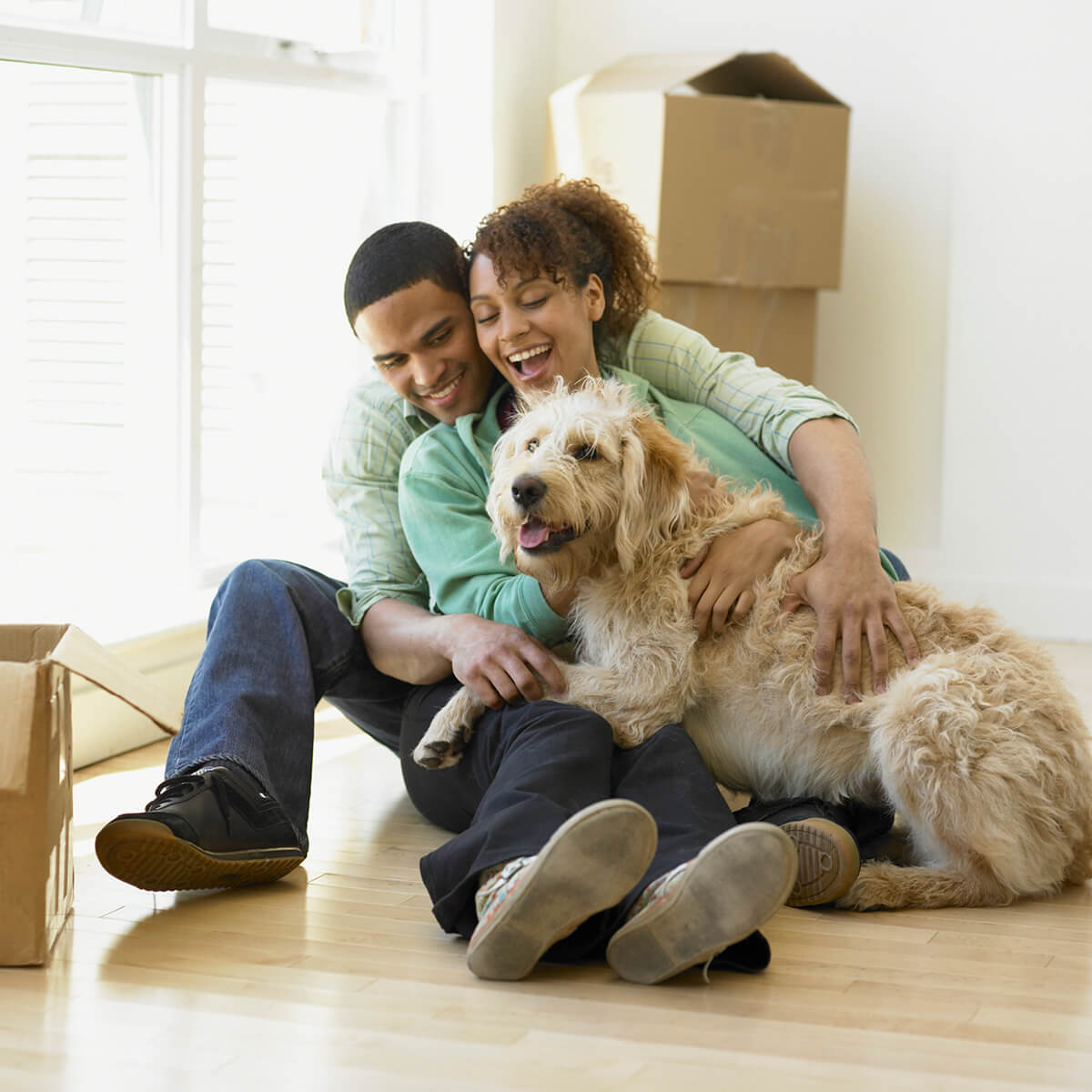 Young couple with dog sitting on floor and moving boxes
